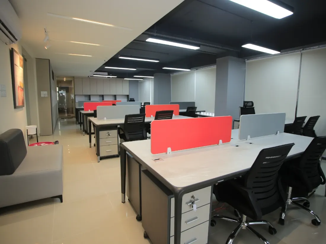 An empty open-plan office with rows of desks and red dividers