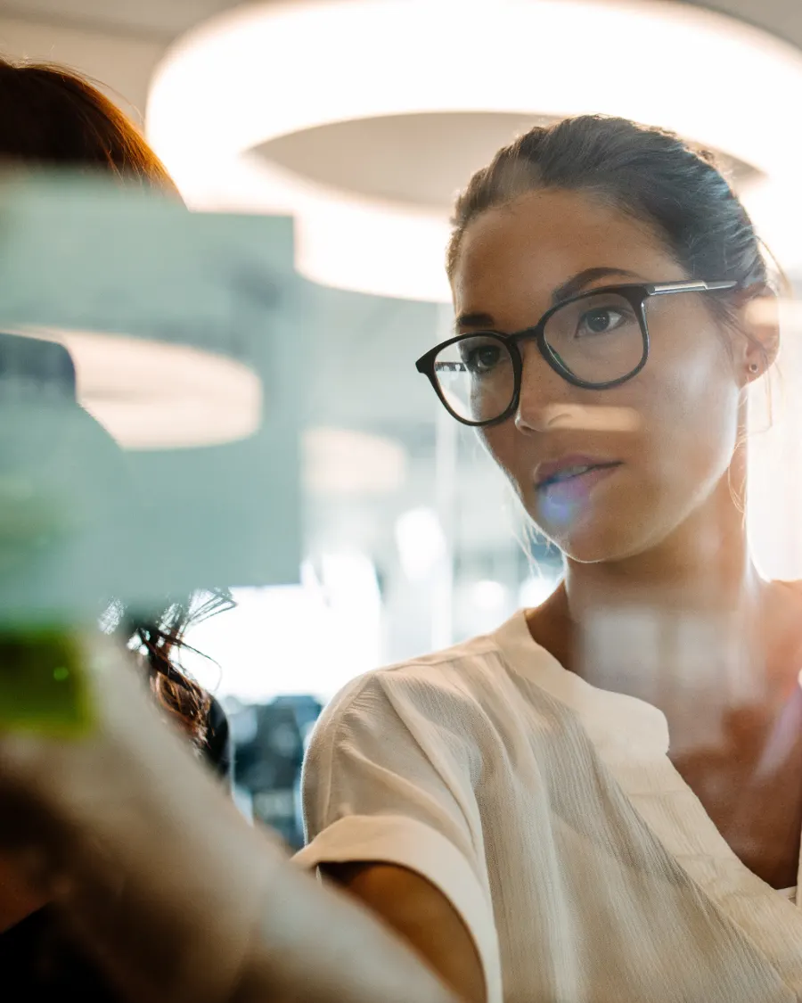 A leader thinking through work on a glass board