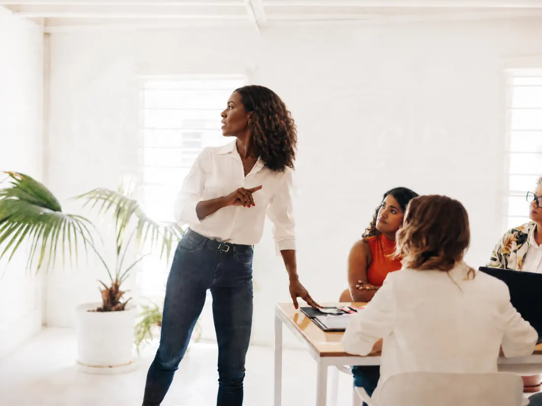A leader standing at the head of the table, directing her team’s attention